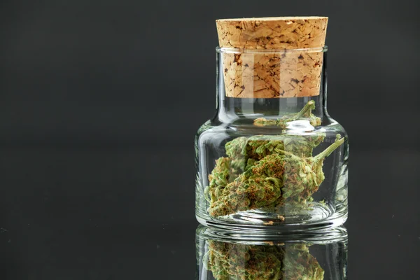 Marihuana Bud Cannabis en tarro de vidrio de cerca sobre fondo negro — Foto de Stock