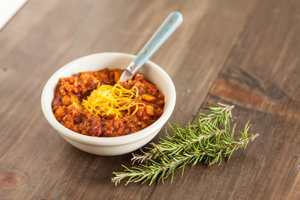 Un tazón caliente de chile vegetariano orgánico picante con queso derretido —  Fotos de Stock