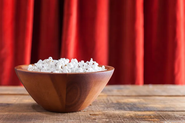 Popcorn in schöner Holzschüssel zum Wathling von Filmen auf Holzhintergrund — Stockfoto