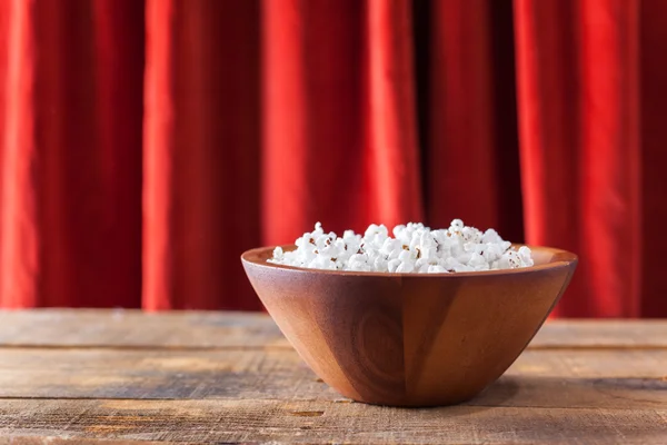 Popcorn in schöner Holzschüssel zum Wathling von Filmen auf Holzhintergrund — Stockfoto