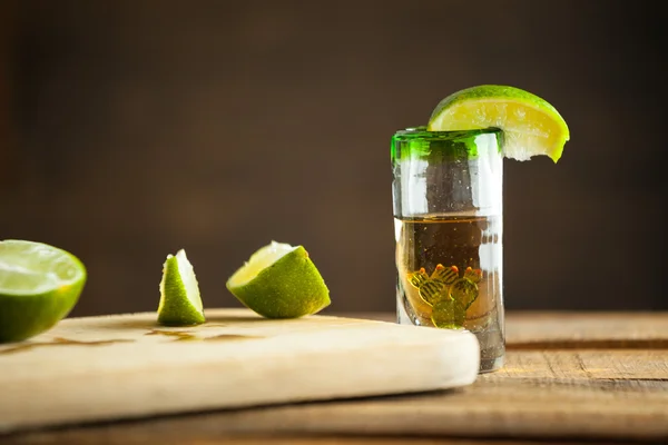 Shot glass of tequila with bottle. Selective focus. Blurred background. — Stock Photo, Image
