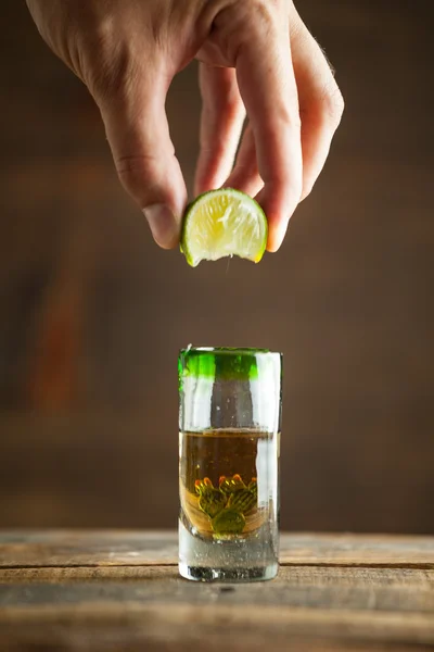 Squeezing lime into shot of tequila. Selective focus. — Stock Photo, Image