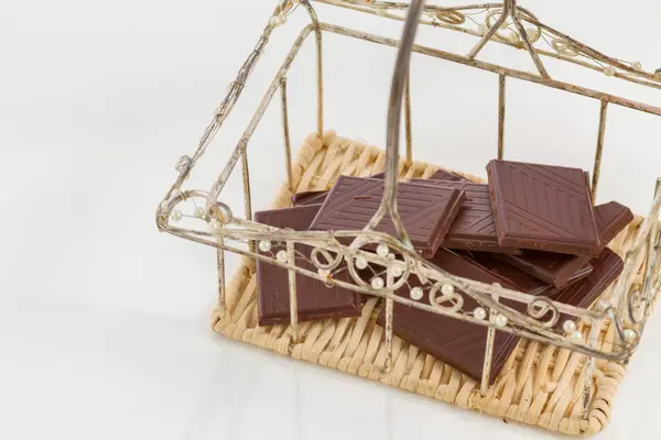Przerwane z gorzkiej czekolady w mały kosz na białym tle — Zdjęcie stockowe