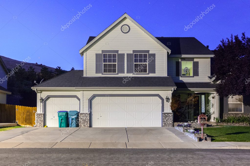 Big Luxury House With Triple Garage Doors At Dusk Night In