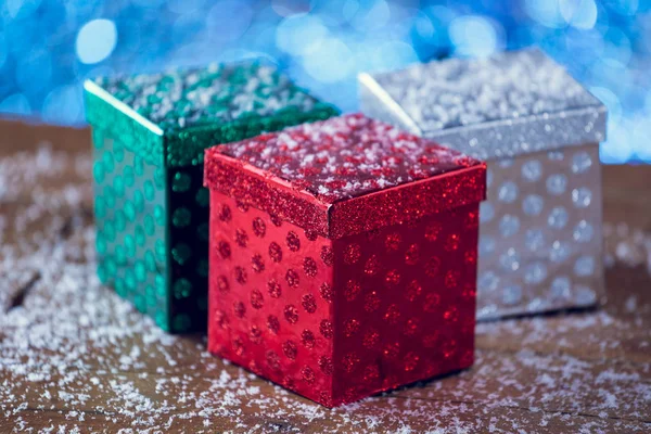 Small Colorful Christmas Gift Boxes On Snowy Wood Background.
