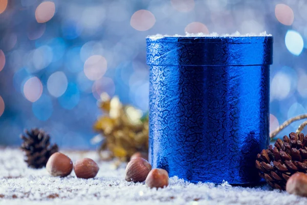 Shiny Blue Round Christmas Gift Box With Decoration On Snowy Wood