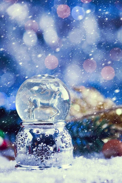 Schnee fällt auf Weihnachten Rentier Schneekugel mit Dekor auf Schnee. Vintage-Filter aufgetragen. — Stockfoto