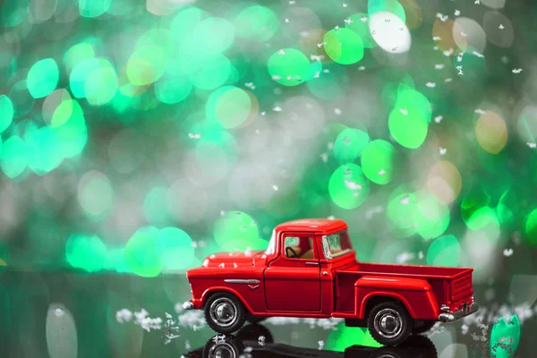Boże Narodzenie zabawki ciężarówki z padającego śniegu na stół szkło tło zielony. — Zdjęcie stockowe