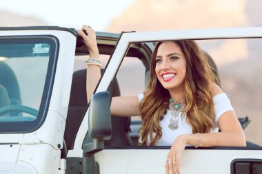Genç gülümseyen güzel kadın arabayla yola oturan.