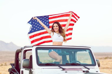 Mutlu genç kız Cabrio araba Amerikan bayrağı sallayarak Holding ayakta.
