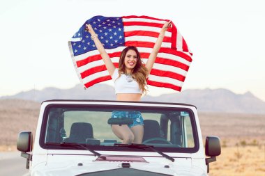 Mutlu genç kız Cabrio araba Amerikan bayrağı sallayarak Holding ayakta.