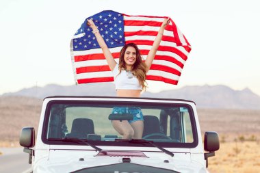 Mutlu genç kız Cabrio araba Amerikan bayrağı sallayarak Holding ayakta.