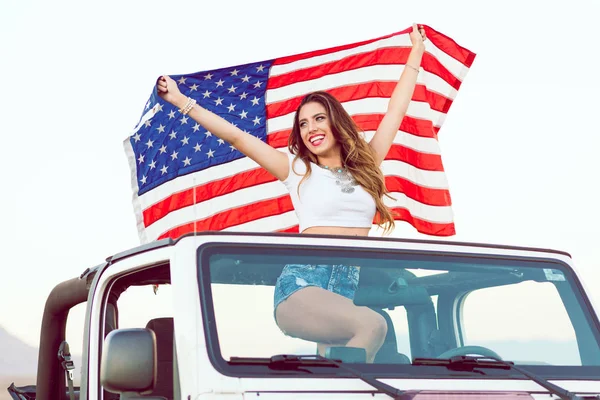 Mutlu genç kız Cabrio araba uzak tutarak ABD bayrağı seyir ayakta. — Stok fotoğraf