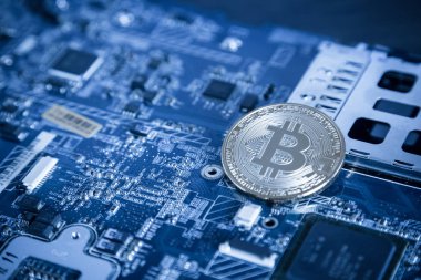 Bilgisayar anakart üzerinde gümüş dijital Cryptocurrency sikke. Bitcoin incelemesi kavramı. Kripto para birimi arka plan.