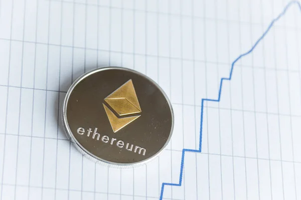 Gold ethereum cryptocurrency coin on spiking blue line graph stock market chart. — Stock Photo, Image