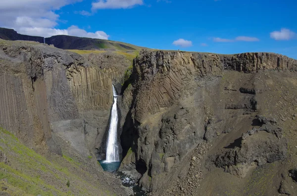 Hengifoss є другою найвищий водоспад на Ісландії. Найбільш спеціальна річ про водоспад є різнокольорові шари в базальтових порід позаду водоспад. — стокове фото