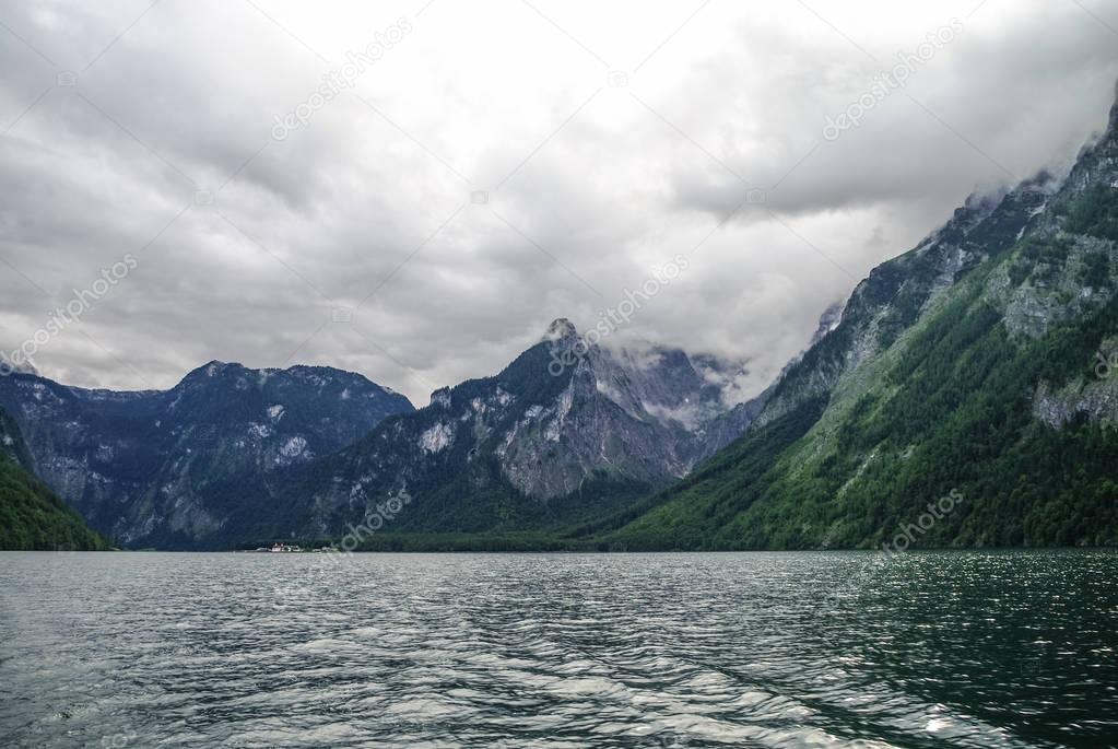 Low clouds over forest and mountains on bank of lake Koenigssee, Bavaria, Germany