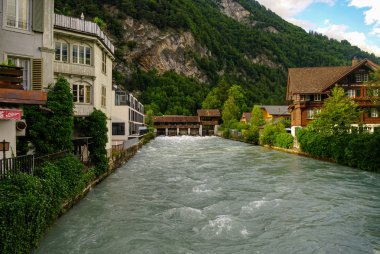 Aare nehri ve eski İsviçre tarzı binalar kıyı boyunca eski kasaba bölgesinde Interlaken 'in dağ arka planına sahiptir.
