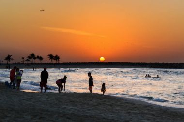 Sahilde günbatımı. Batan güneşin zemin karşı insan siluetleri