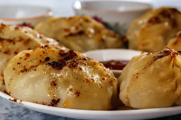 Manti dans une assiette avec sauce. Nourriture traditionnelle des habitants d'Asie centrale. Gros plan — Photo