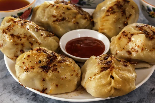 Manti dans une assiette avec sauce. Nourriture traditionnelle des habitants de l'Asie centrale — Photo