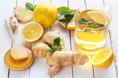 Çay, limon, zencefil, bal ve nane beyaz tahtalar üzerinde