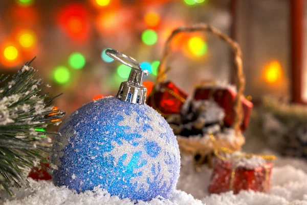 Brinquedos de Natal na neve, uma lanterna vermelha com uma vela, uma grinalda de luzes, um bokeh — Fotografia de Stock