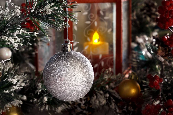 Bir mum ile kırmızı bir fener karşı bir Noel ağacının dalını asılı beyaz parlak top — Stok fotoğraf