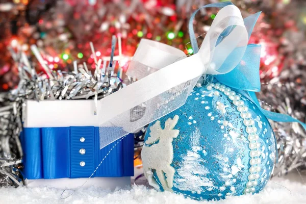 圣诞礼物和圣诞球背景下的闪亮金属丝的雪地上。发光灯 免版税图库图片