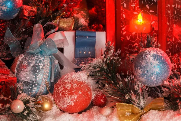 Palle e campana di Natale sono coperti di neve alla luce di una lanterna rossa sullo sfondo del paesaggio di Capodanno — Foto Stock