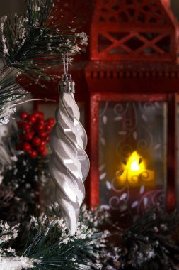 bir mum ile kırmızı bir fener karşı bir Noel ağacının dalını asılı beyaz buz saçağı