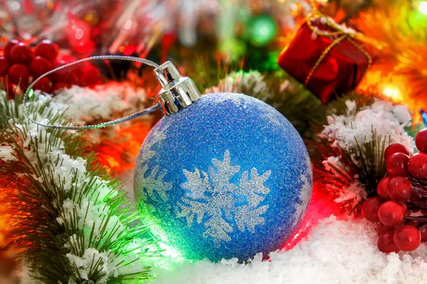 Bal op de besneeuwde takken van een kerstboom tegen een achtergrond van glanzende klatergoud. gloeiende lichten. bokeh — Stockfoto