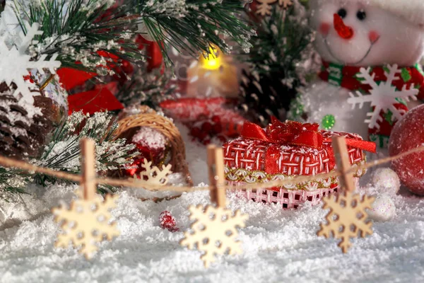 Presentes de Natal na neve, flocos de neve em rodadas de roupa, boneco de neve alegre e lanterna vermelha no fundo da paisagem de Ano Novo — Fotografia de Stock