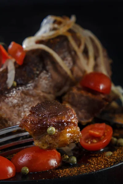 Cordero frito con verduras. Carne frita sobre fondo negro. Trozo de carne en el tenedor —  Fotos de Stock