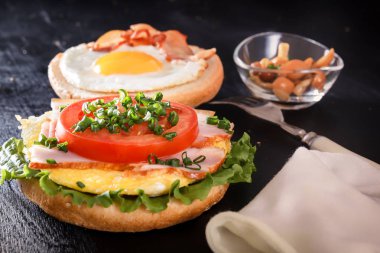 Kahvaltı. Kızarmış yumurta rulo üzerinde domates, yeşillik, jambon, mantar. Çatal bıçak takımı. Yakın çekim siyah arka plan