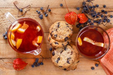 Yulaf ezmeli kurabiye ve limonlu kırmızı çay. Vahşi orman meyveleri, physalis ahşap bir masa üzerinde. Yukarıdan görüntülemek