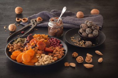 Kurutulmuş meyve, enerji ısırıkları, çikolata ezmesi ve fındık karışımı siyah bir masa. Alçak tuş