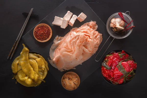 La col fermentada kimchi, los pimientos rojos y amarillos picantes con el tofu a la mesa negra - la comida tradicional coreana. Vista superior — Foto de Stock