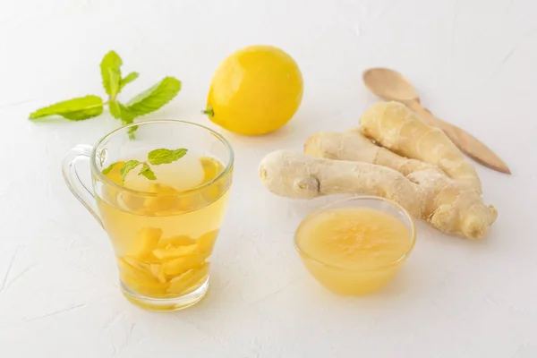Thé au gingembre au citron, miel et menthe sur une table en bois blanc — Photo