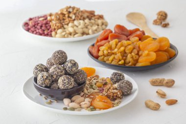 Doğal sağlıklı çiğ enerji ısırıkları, çikolata ezmesi ve beyaz bir masada fındıklı kurutulmuş meyve karışımı.