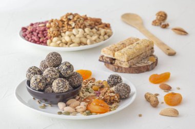 Doğal sağlıklı çiğ enerji ısırıkları, çikolata ezmesi ve beyaz bir masada fındıklı kurutulmuş meyve karışımı.