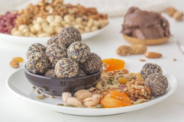 Doğal sağlıklı çiğ enerji ısırıkları, çikolata ezmesi ve beyaz bir masada fındıklı kurutulmuş meyve karışımı. Yakın plan.