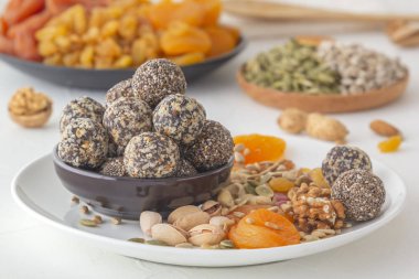 Doğal sağlıklı çiğ enerji ısırıkları, çikolata ezmesi ve beyaz bir masada fındıklı kurutulmuş meyve karışımı. Yakın plan.