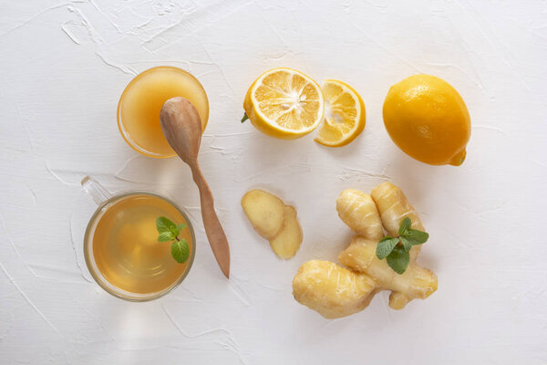Чай с имбирем, мятой, лимоном и медом на белом деревянном столе. Вид сверху
