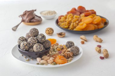 Doğal sağlıklı çiğ enerji ısırıkları, çikolata ezmesi ve beyaz bir masada fındıklı kurutulmuş meyve karışımı.