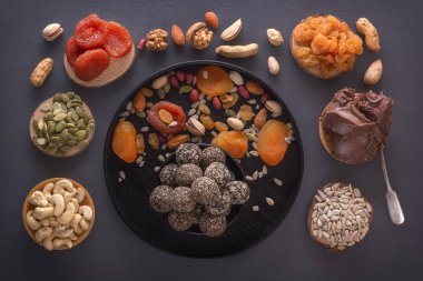 Doğal sağlıklı çiğ enerji ısırıkları, çikolata ezmesi ve kurutulmuş meyve karışımı karanlık bir masada fındık. Üst görünüm