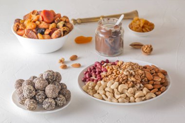 Doğal sağlıklı çiğ enerji ısırıkları, çikolata ezmesi ve beyaz bir masada fındıklı kurutulmuş meyve karışımı.