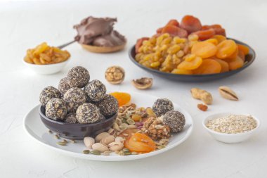 Doğal sağlıklı çiğ enerji ısırıkları, çikolata ezmesi ve beyaz bir masada fındıklı kurutulmuş meyve karışımı.