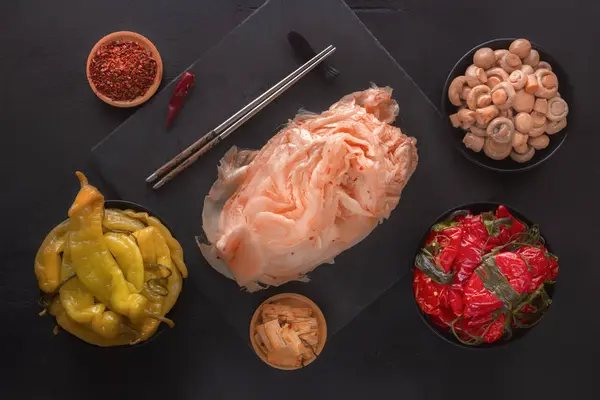 La col fermentada kimchi, los pimientos rojos y amarillos sobre la mesa negra - la comida tradicional coreana. Vista superior — Foto de Stock