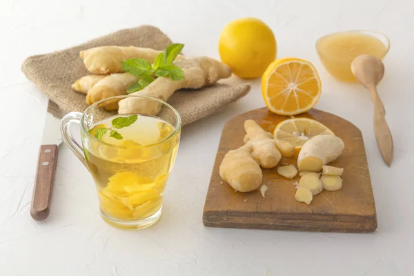 Thé au gingembre au citron, miel et menthe sur une table en bois blanc — Photo